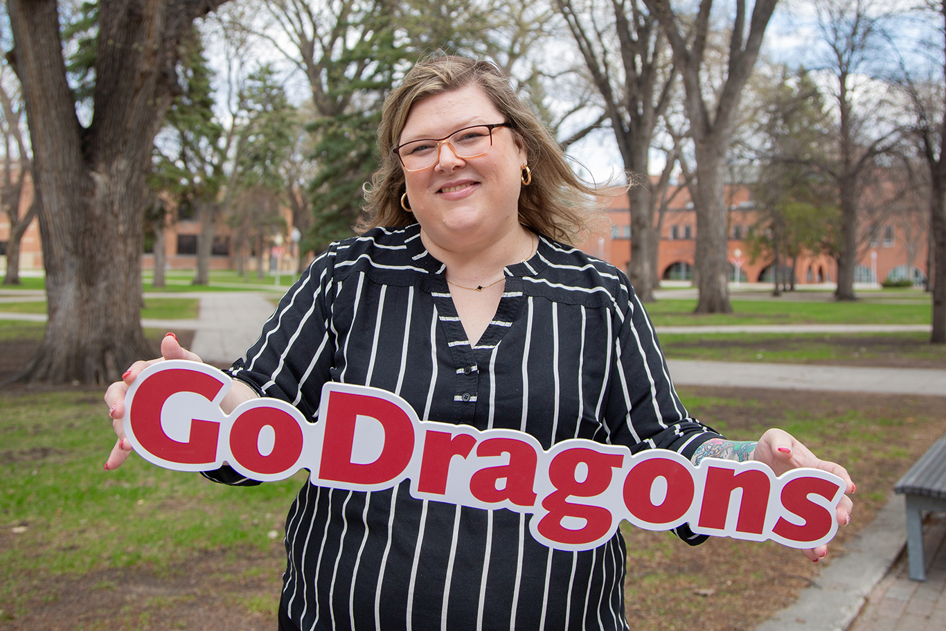 Amanda Larson smiles while holding a sign that reads "Go Dragons"