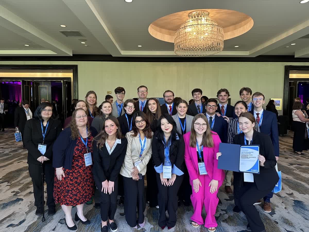 A group of 20 students pose while one holds a certificate indicating the Chapter's status as a top 10 chapter in Collegiate DECA. 