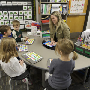 A teacher at a table with several elementary school aged children