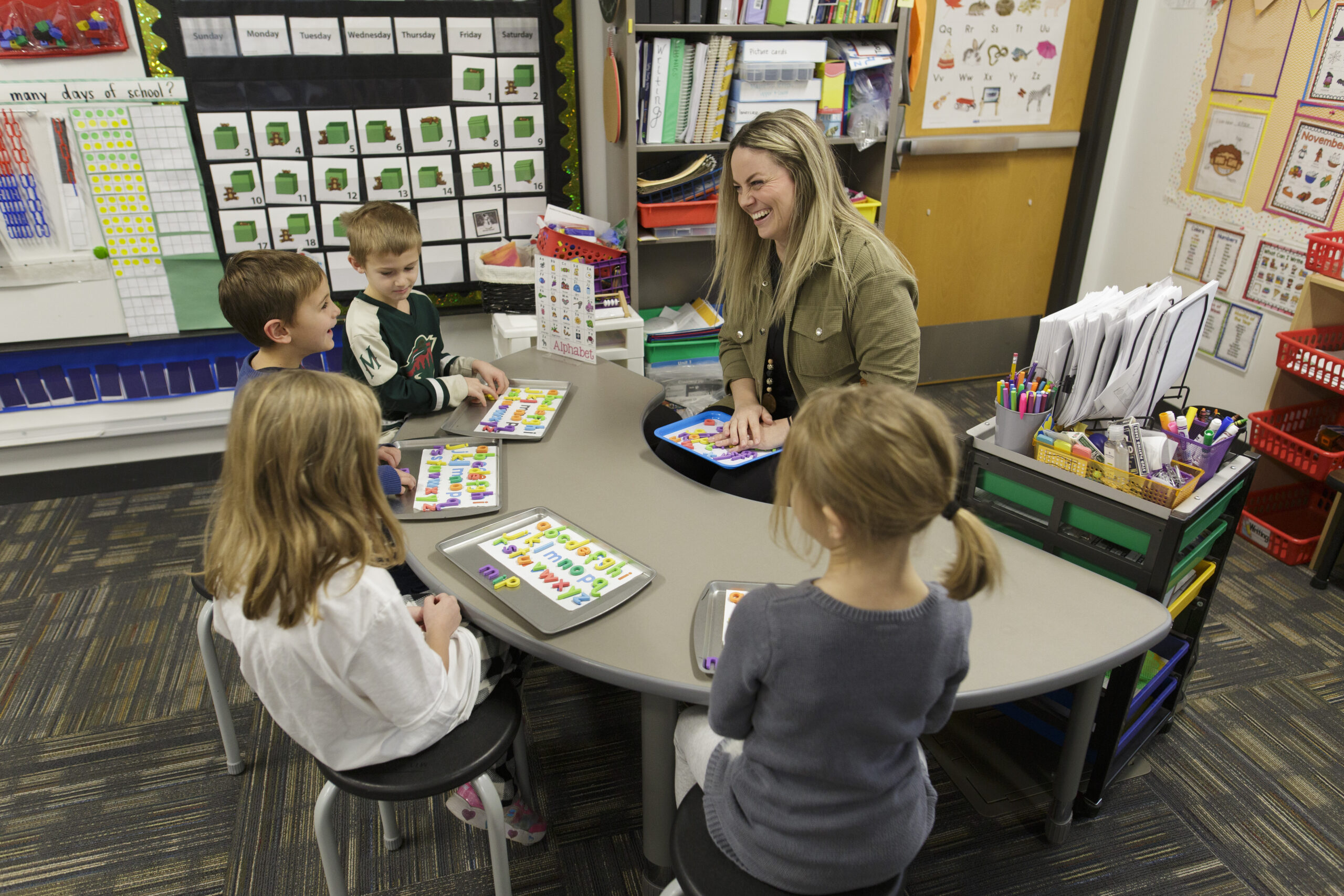 A teacher at a table with several elementary school aged children