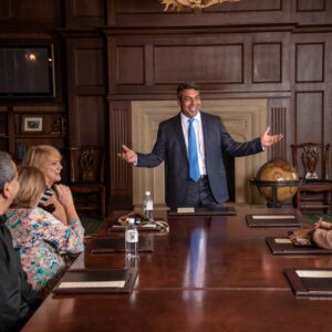 Moorhead finance alum Najam Usmani talks to people at a boardroom table.